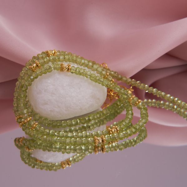 Detailansicht der 3 mm großen, facettierten Peridot-Rondelle im Wechsel mit vergoldeten Rädchen und gelaserten Silberkügelchen.
